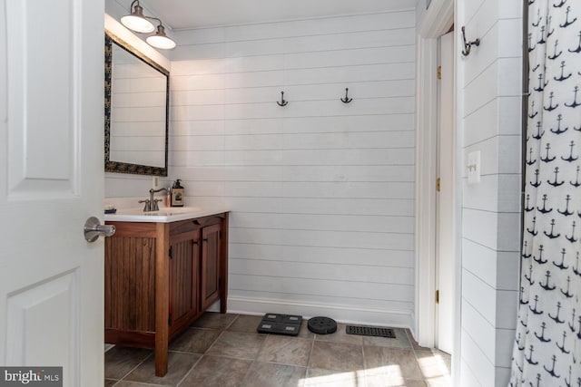 bathroom with vanity and wooden walls