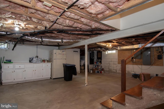 basement with electric panel and white refrigerator