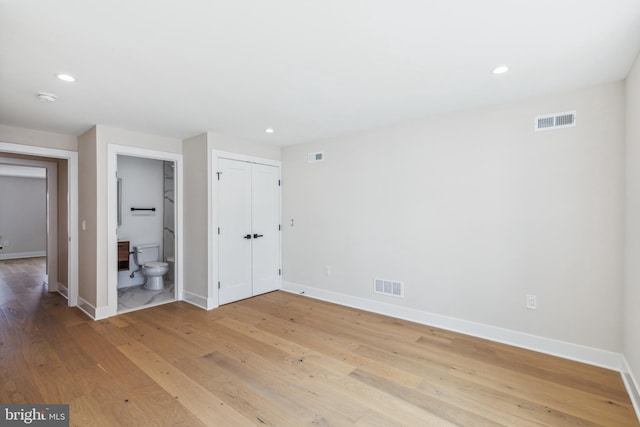 interior space with connected bathroom, light hardwood / wood-style flooring, and a closet