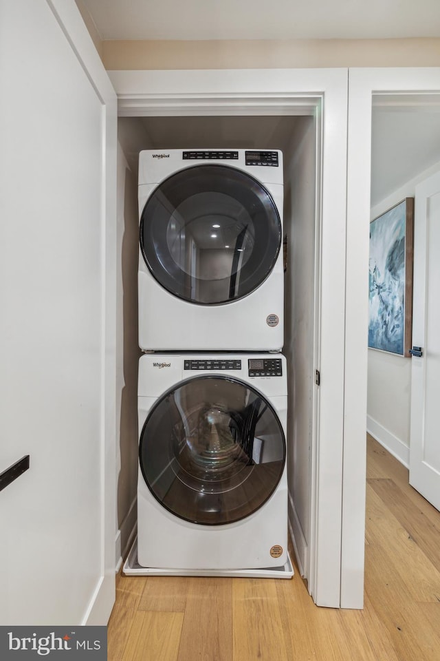 laundry room with light hardwood / wood-style flooring and stacked washing maching and dryer