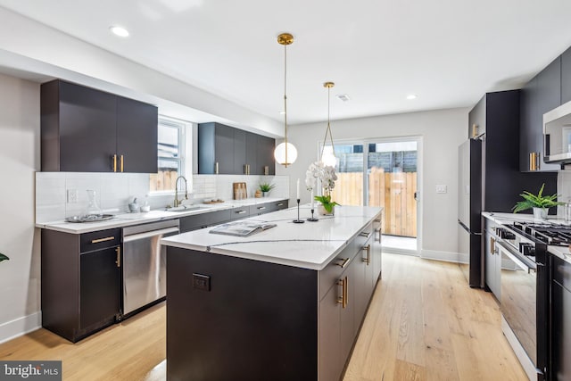 kitchen with light wood-type flooring, tasteful backsplash, a kitchen island, appliances with stainless steel finishes, and decorative light fixtures