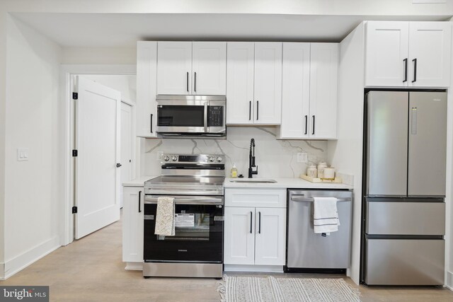 kitchen with stainless steel appliances, white cabinets, tasteful backsplash, and sink