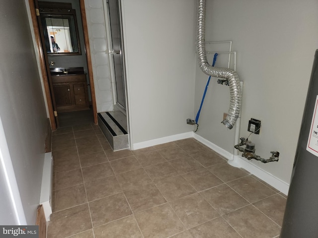 clothes washing area featuring tile patterned flooring and water heater