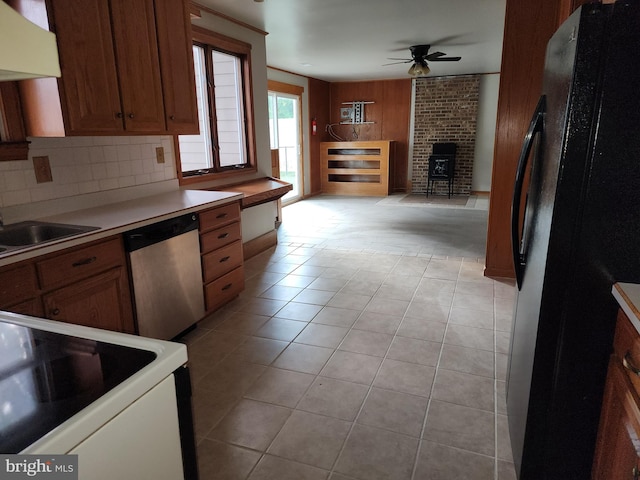 kitchen featuring a wood stove, white electric stove, ceiling fan, stainless steel dishwasher, and black fridge