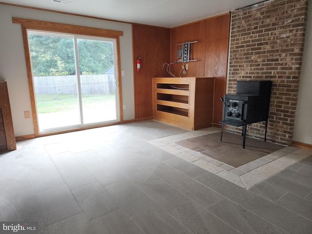 unfurnished living room featuring a wood stove and wood walls