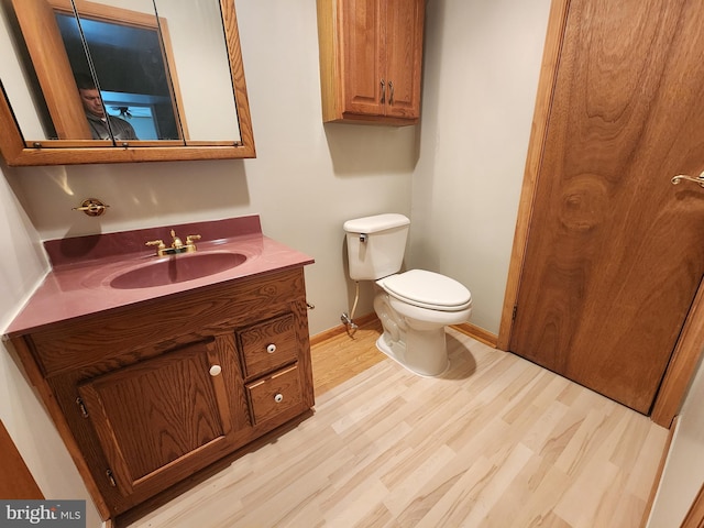 bathroom with vanity, toilet, and hardwood / wood-style flooring