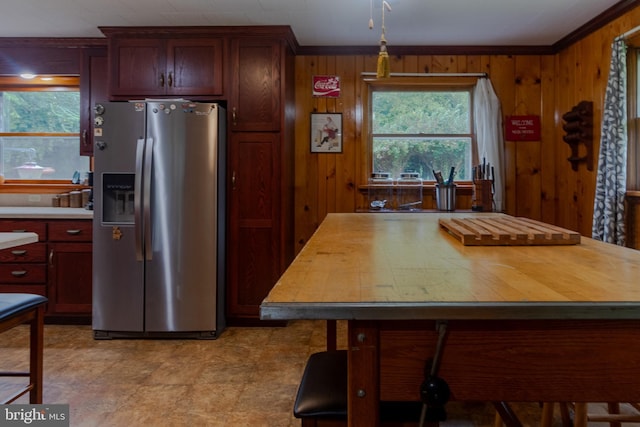 kitchen with stainless steel refrigerator with ice dispenser, wood walls, and crown molding