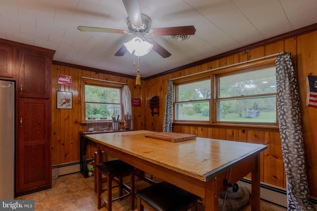 dining room with crown molding, wood walls, ceiling fan, and a baseboard heating unit