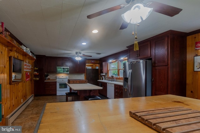 kitchen with a baseboard heating unit, wood walls, kitchen peninsula, and appliances with stainless steel finishes