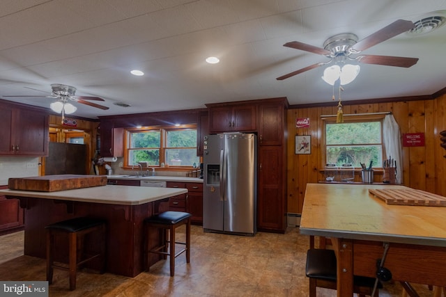 kitchen featuring wood walls, black fridge, plenty of natural light, and stainless steel fridge