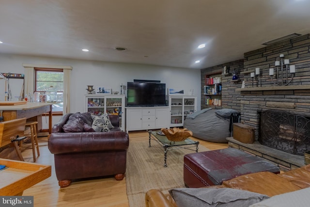 living room featuring a stone fireplace and light hardwood / wood-style flooring