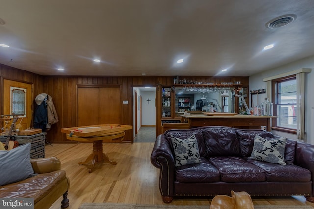 living room featuring light wood-type flooring and wooden walls