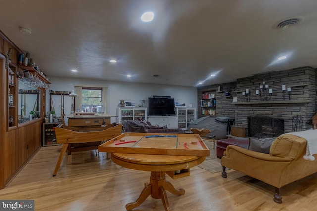 living room featuring wooden walls, light wood-type flooring, and a fireplace