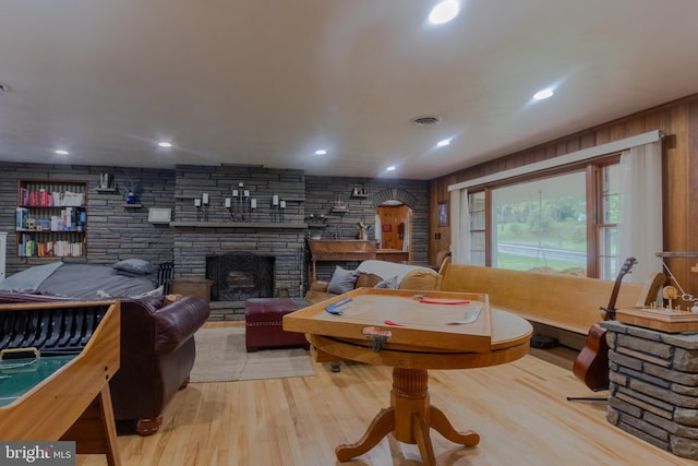 playroom featuring a fireplace, wood walls, and light hardwood / wood-style flooring