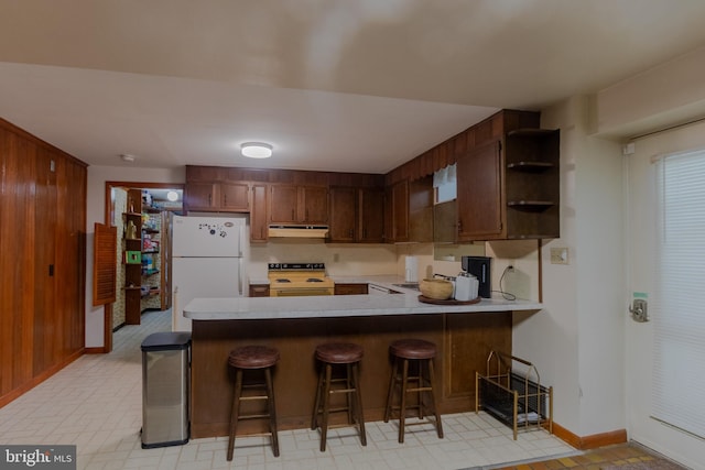 kitchen featuring white appliances, a breakfast bar area, sink, and kitchen peninsula