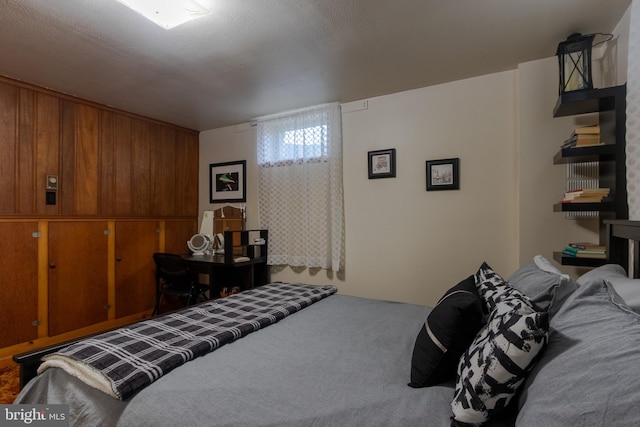 carpeted bedroom featuring wood walls and a textured ceiling