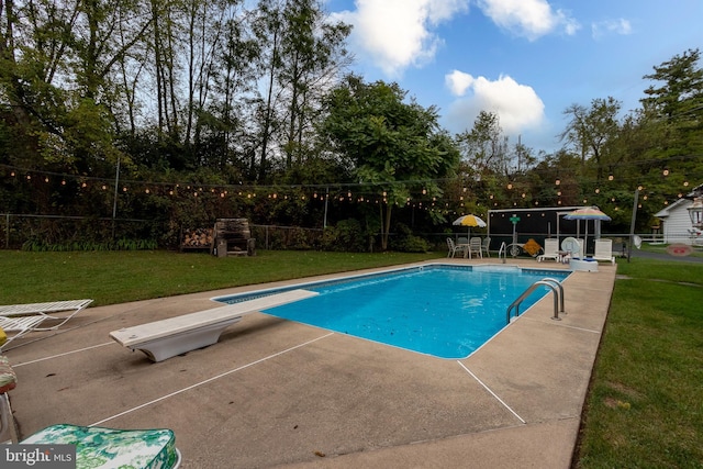 view of swimming pool featuring a lawn, a patio area, and a diving board