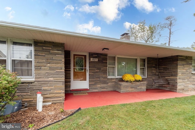 view of exterior entry featuring a lawn