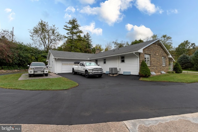 view of property exterior featuring a lawn, a garage, and central AC unit