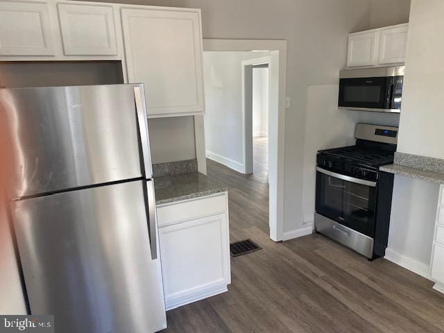 kitchen with dark wood-type flooring, appliances with stainless steel finishes, and white cabinets