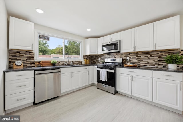 kitchen with white cabinets, appliances with stainless steel finishes, sink, and tasteful backsplash