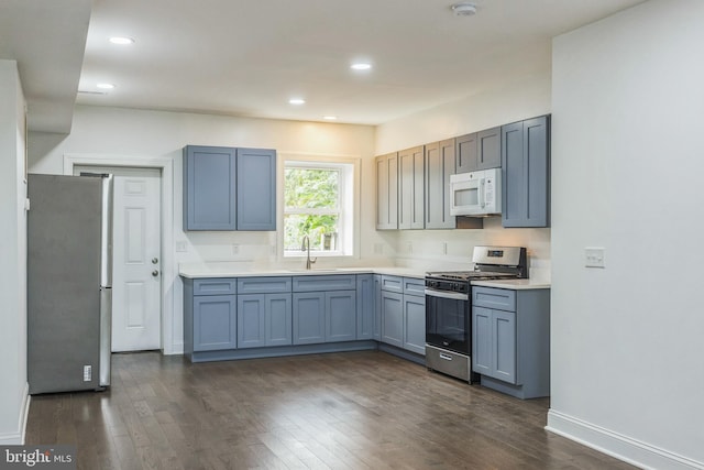 kitchen with appliances with stainless steel finishes, sink, and dark wood-type flooring