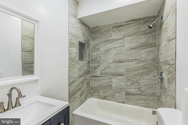 full bathroom featuring tiled shower / bath, vanity, and toilet