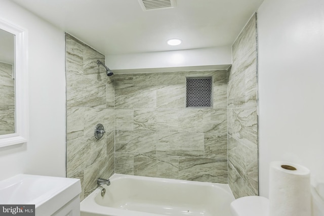 full bathroom featuring vanity, tiled shower / bath combo, and toilet