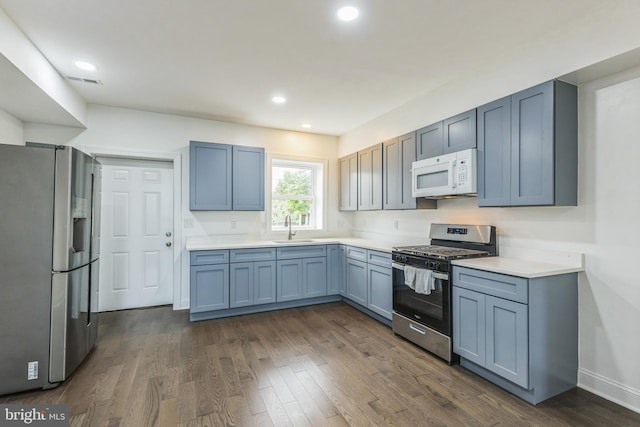 kitchen with appliances with stainless steel finishes, dark wood-type flooring, and sink