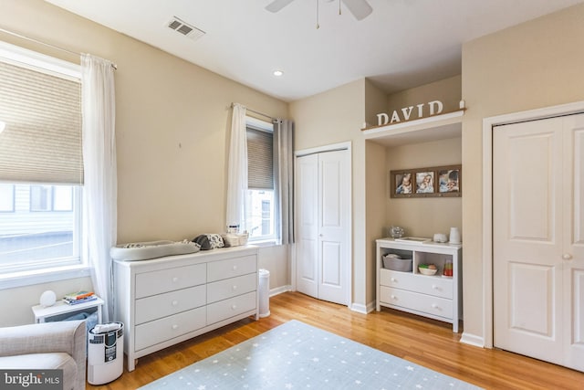 bedroom featuring light wood-type flooring, two closets, and ceiling fan