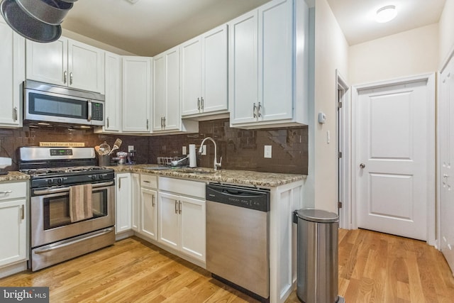 kitchen featuring appliances with stainless steel finishes, white cabinetry, light stone countertops, and light hardwood / wood-style flooring