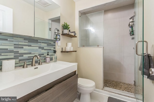 bathroom featuring tile patterned flooring, tasteful backsplash, walk in shower, vanity, and toilet