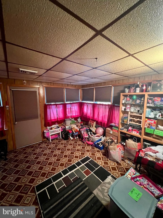 miscellaneous room with a drop ceiling and dark colored carpet