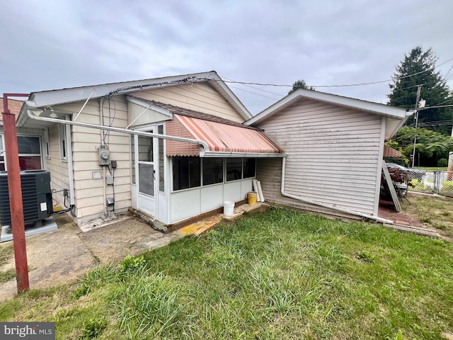 rear view of house featuring a lawn and central air condition unit