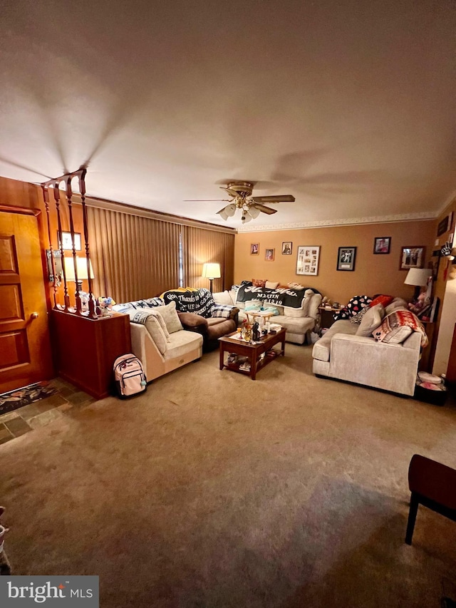 carpeted living room with ceiling fan, crown molding, and wood walls