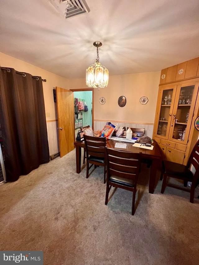 dining space featuring wooden walls, a chandelier, and carpet