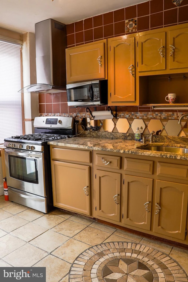 kitchen with light tile patterned floors, sink, wall chimney exhaust hood, appliances with stainless steel finishes, and decorative backsplash