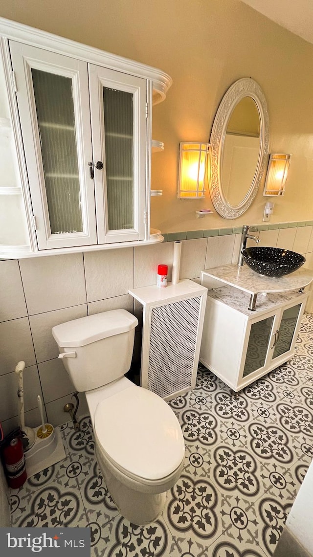 bathroom with tile walls, sink, and toilet