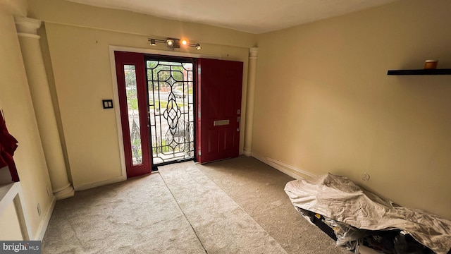 foyer entrance with light colored carpet and decorative columns