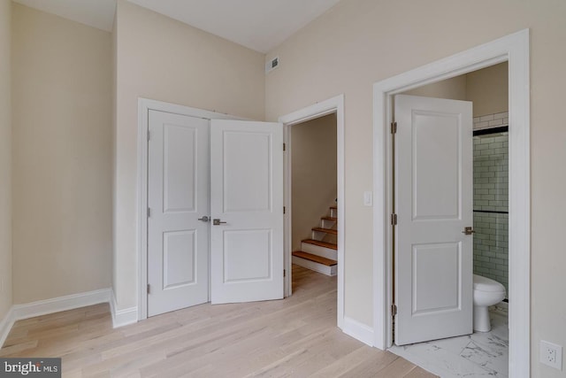 unfurnished bedroom with light wood-type flooring and ensuite bath