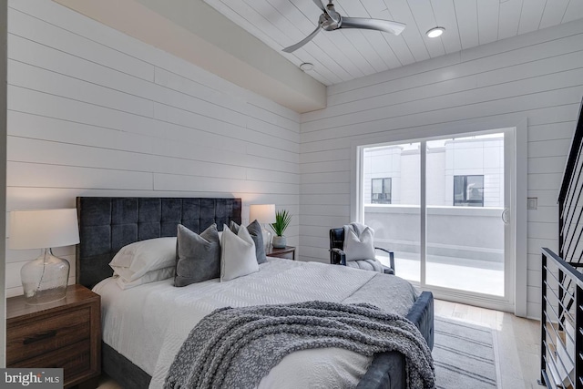 bedroom with access to outside, ceiling fan, light hardwood / wood-style floors, and wood walls