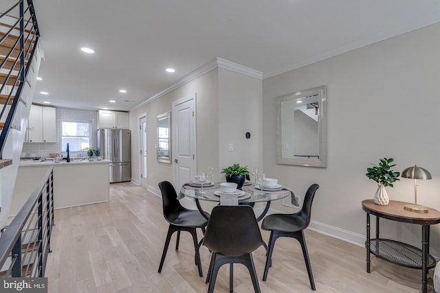 dining space with crown molding, sink, and light hardwood / wood-style floors