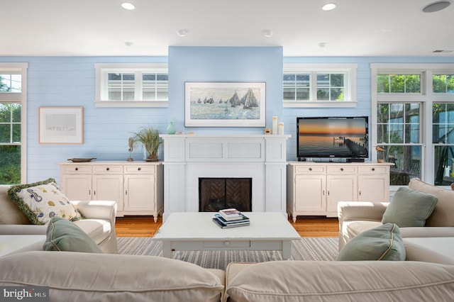 living room with light hardwood / wood-style flooring and wooden walls