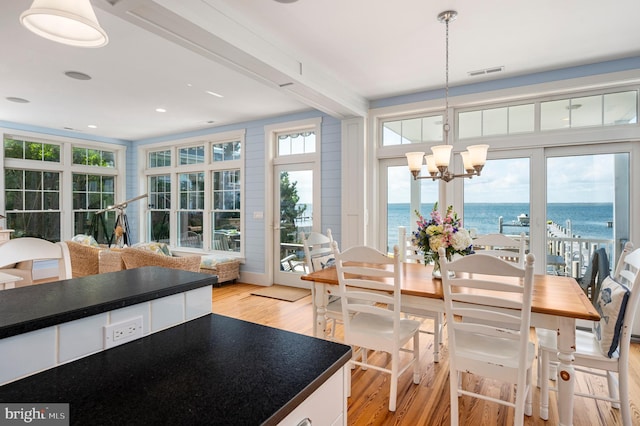 sunroom with a water view, beamed ceiling, and a chandelier