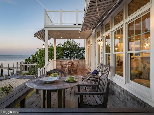 deck at dusk featuring a water view