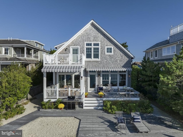 rear view of house featuring a balcony and a wooden deck