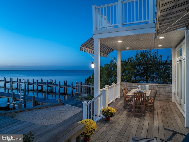 deck at dusk featuring a boat dock and a water view