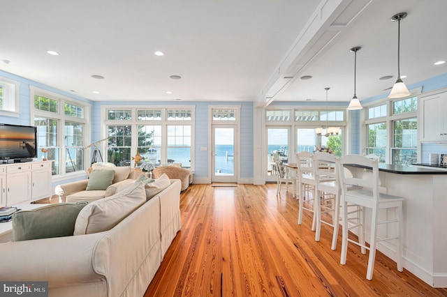 living room with ornamental molding, light wood-type flooring, plenty of natural light, and a chandelier