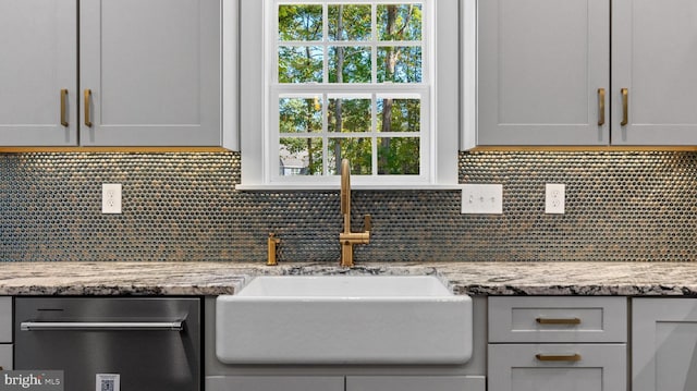 kitchen featuring light stone countertops, tasteful backsplash, and sink