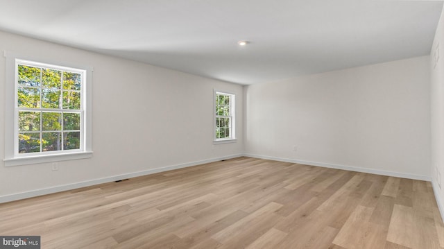 spare room featuring a healthy amount of sunlight and light hardwood / wood-style floors